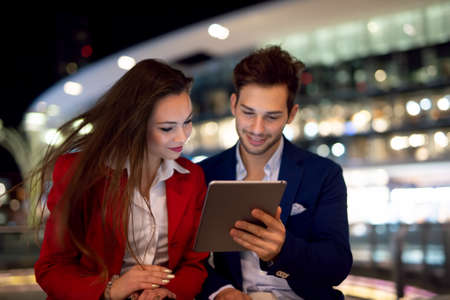 Business people using tablet at night in a cityの写真素材