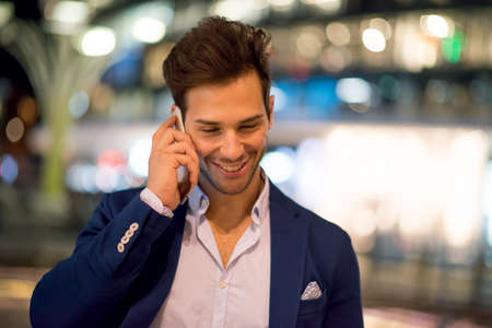 Young handsome man talking on the cell hone at nightの写真素材