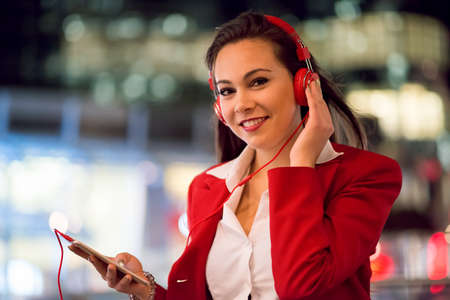 Woman listening music from her cellphone at nightの写真素材