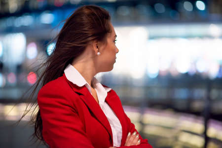 Portrait of a young business woman waiting outdoors in a city at night timeの写真素材