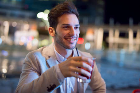 Smiling business man drinking a cocktail after workの写真素材