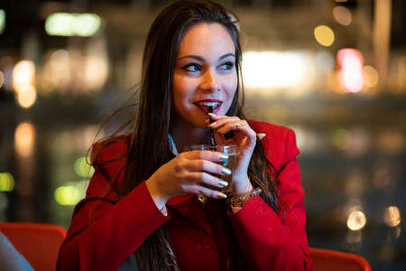 Young woman holding a drink at a night club outdoorの写真素材