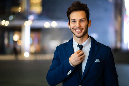 Young businessman adjusting his look outdoor in the eveningの写真素材