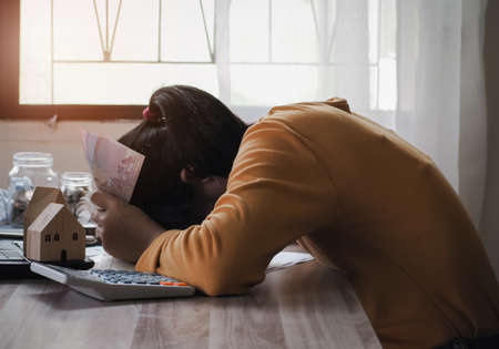 woman holding banknotes money sleeping on desk in office room. concept work from home.の写真素材