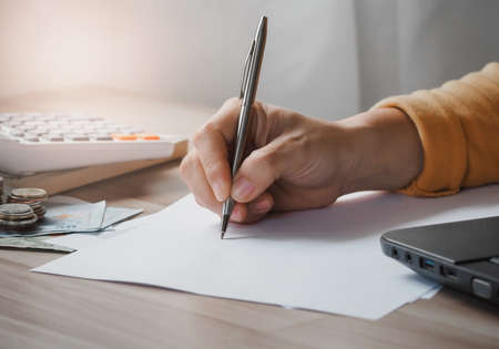 Hand of businesswoman writing on paper and office supplies on desk of working. Business Education conceptの写真素材