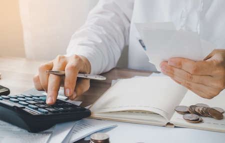 young woman using calculator calculating monthly home expenses, taxes, bank account balance and credit card bills payment, concept saving money.の写真素材