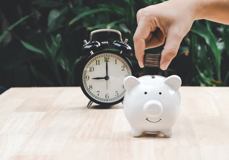 People hands puts a coin in a pink piggy bank. The concept of saving money or savings, investmentの写真素材