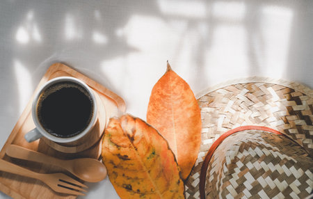 Coffee mug, leaves, Straw hat on white background. Morning Minimal template. Autumn winter vintage concept.の写真素材