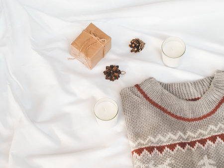 Cozy autumn or winter concept. candles, gift box with pine decoration, sweater on white background. minimal concept. top view, vintageの写真素材