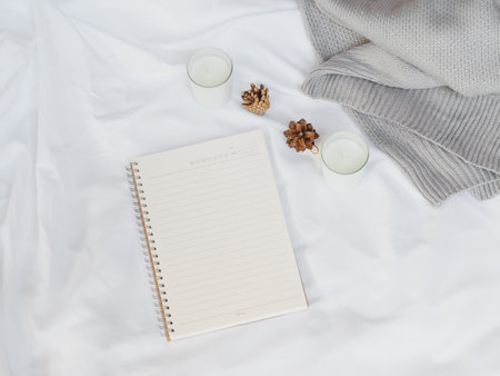 Cozy autumn or winter concept. white paper note, candles with pine decoration, sweater on white background. minimal concept. top view, vintageの写真素材