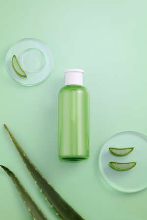Background Green with natural cosmetics of aloe vera extract. Cosmetics on green table with aloe vera in petri, tubeの写真素材