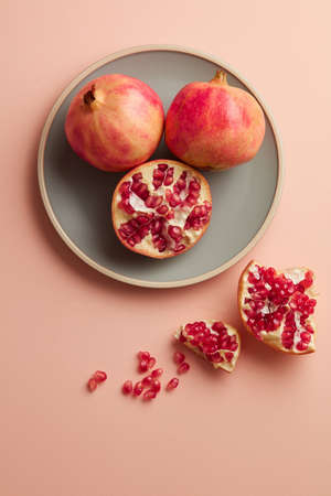 Pomegranates on a grey tray on pastel pink background. Minimal style. Top view. Copy spaceの写真素材