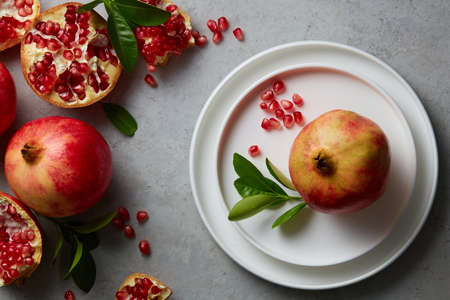 Empty background for cosmetics with pomegranate extract. Whole pomegranate and pomegranate seeds on podium circle on color background. Top view. Flat lay image.の写真素材