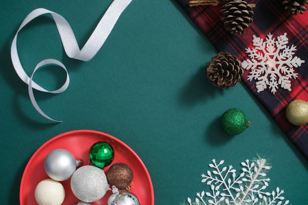 Dark green background with decorations of Xmas day. Top view of snowflakes with baubles, ribbon and...