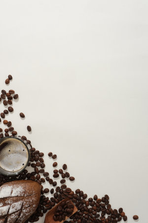 Creative background for advertising with blank space for design make from coffee beans. On a white background, cup of coffee, bread and coffee beans decorated on lower left corner. Top viewの写真素材