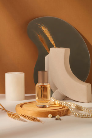Background for branding and packaging presentation perfume product. A glass bottle without label on wooden podium displayed with pearl necklace, candle and wheat on brown background. Front viewの写真素材
