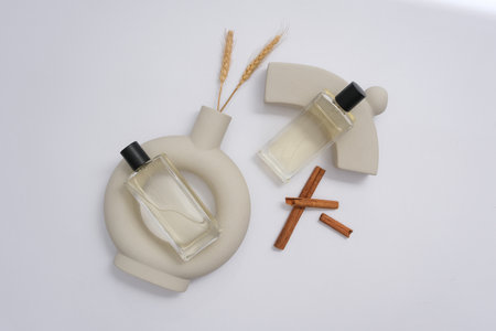 Bottles of cosmetic essential oil on white background with cinnamon sticks, gray vases and wheat...