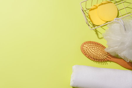 View from above of a towel, a detangling comb, a sponge and two sponges in an iron basket on a pastel background. Empty space for displaying body care products.の写真素材