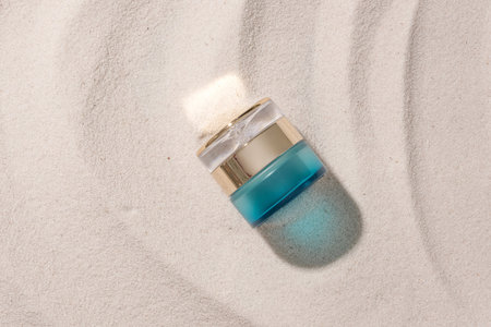 Flat lay of a cosmetic jar with luxury design isolated on smooth sand background. Copy space for cosmetics advertising. Exquisite mockup with summer mood.の写真素材