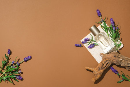 A transparent perfume bottle is displayed on a white podium, lavender flowers are decorated on a brown background. Ideal space for product display and design.の写真素材
