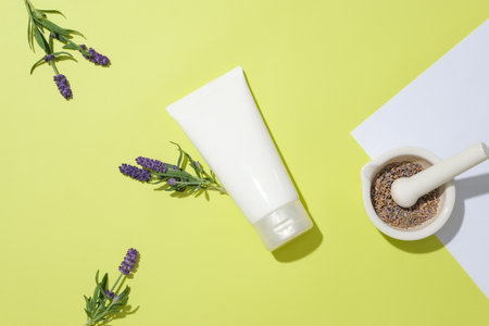 An unlabeled cosmetic tube is in the center of the frame, surrounded by decorations of lavender flowers and dried lavender buds inside a ceramic mortar. Mockup of natural cosmetics.の写真素材