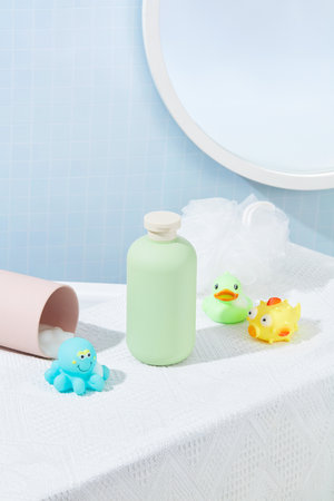 Close-up of a cosmetic bottle, a bath sponge and silicone bath toys displayed on a table covered...