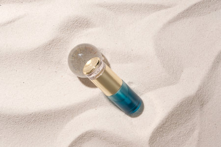 View from above of a luxury cosmetic bottle placed next to a glass ball on a white sand background. Mockups for advertising. Minimalist natural space.の写真素材