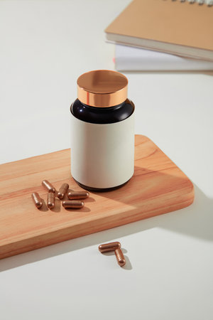 Close-up of a bottle of dietary supplements placed on a wooden platform with hard capsules on a...
