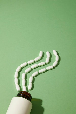 White pills arranged in a wavy shape were poured from an unlabeled pill bottle. Mockup for medicine advertising. Medicines have the effect of regulating one or several functions of the body.の写真素材