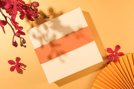 Close up of a gift box, paper fan and red orchids standing out on a pastel background. Tet theme for advertising. Mockup for design and holiday decoration.の写真素材