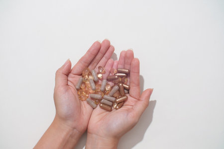 Two hands together holding capsules on white background. Vitamins are produced in capsule form for easy storage and absorption by the body. Medicine space.の写真素材