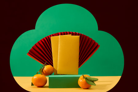Lucky money envelopes, tangerines and a paper fan are displayed on a turquoise podium. Copy space for ads with front view. Characteristics of Tet holiday.の写真素材
