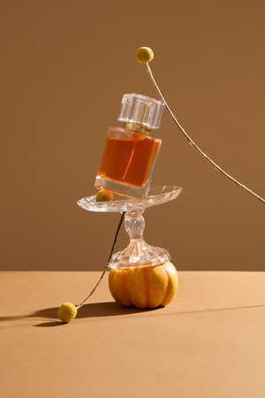 Cozy vibe with glass perfume bottle stacked on a glass object and a pumpkin. Autumn is one of the...