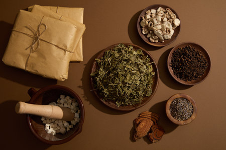 A mortar filled with Poria cocos, few wooden dishes containing Sand ginger, Dried mint, Cloves and...