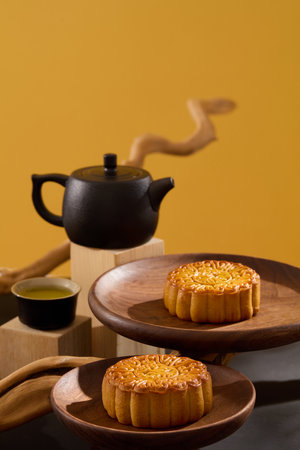 Mid-autumn festival celebration with delightful mooncakes displayed on few round-shaped dishes. Black teapot and teacup are arranged. Happy Mid Autumn Festivalの写真素材