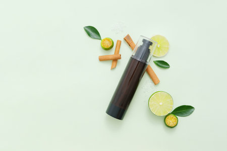 Few cinnamon sticks, slices of lime and kumquat arranged on light background with unbranded bottle. Copy space. Lime and Kumquat are rich in vitamin C and antioxidantsの写真素材