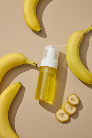 Empty label bottle filled with yellow liquid and bananas are featured. Banana (Musaceae) face masks help hydrate oily skin thus combating acneの写真素材