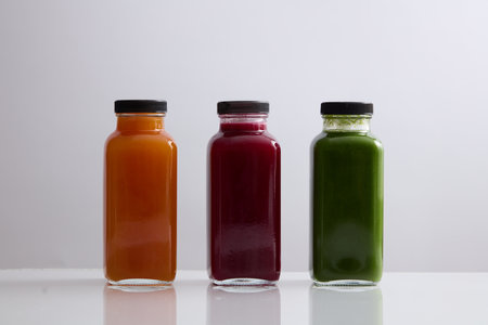 Front view of three blank label glass bottle filled with juice in orange, red and green color. Mockup design of healthy beverage brands. Organic juice conceptの写真素材