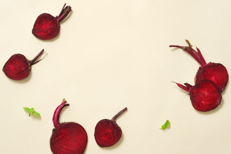 Slices of beetroot are arranged with small green leaves over light background. Beetroot (Beta vulgaris) may delay signs of premature agingの写真素材