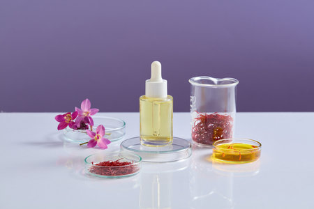 Round podium with a dropper bottle placed on. Few glass petri dishes featured Crocus flowers, liquid and saffron. Science laboratory research and development conceptの写真素材