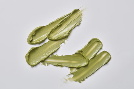 Top view of cream streaks randomly drawn on a white background with the same texture of the mask....