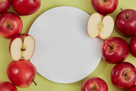 Pedestal for cosmetic product and packaging mockups display presentation and a lot of ripe red apples decorated on green background. Round white podium form an empty space to place your designの写真素材