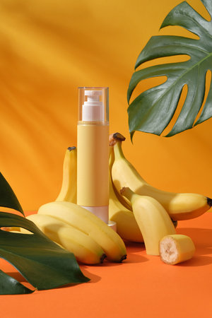 Mockup scene for advertising cosmetic of banana extract - pump bottle unbranded surround by ripe yellow bananas and green monstera leaves on a yellow background with leaf shadowの写真素材