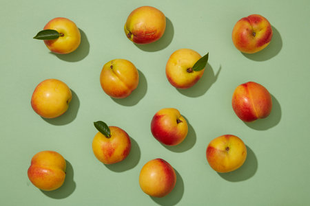 Top down flat lay colorful shot with fresh ripe peaches (prunus persica) on pastel green background....