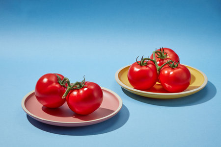 Scene for advertising cosmetic products of tomato extract - round plated containing red fresh tomatoes on a blue background. Tomatoes have a lot of nutrients that are good for healthの写真素材
