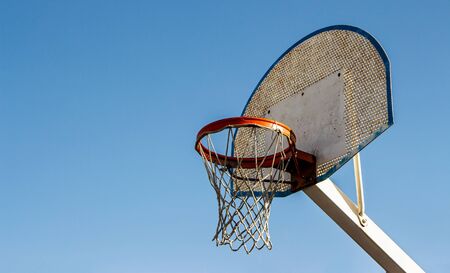 Vintage basketball ring in a street courts with a blue sky background. Down view. Selective Focus.