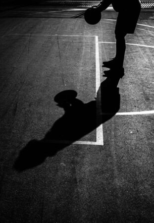 Silhouette of man preparing a free throw in a basketball game. B&W. Copy space.