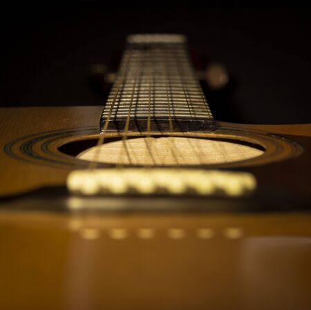 Acoustic guitar close-up view with a black background. Selective focus.