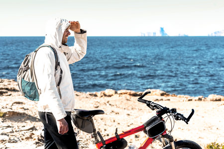 young man riding a red bike, watching the sunrise in the countrysideの写真素材