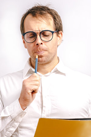Young man looking at a yellow folder drinking coffee in a blues cup. White background.の写真素材